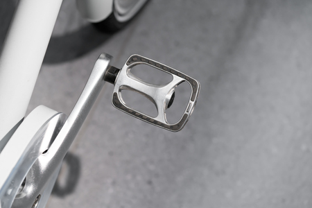 Closed up silver metal bicycle paddle against cement floor.