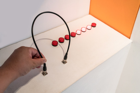 Hand plugging in a black cable into an input outlet. Experiment and education concept.