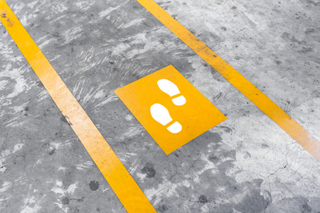 Walkway lane in parking building. Painted yellow footsteps between parallel yellow lines on abstract...