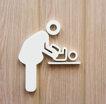 Woman and baby symbol changing diapers against wooden background.の写真素材
