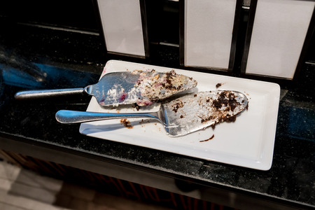 Used silver metal cake server on white porcelain plate by dessert bar in hotel dinner buffet.の写真素材