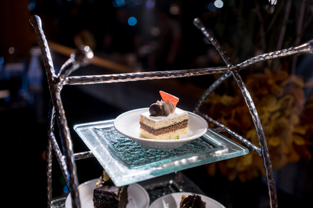 Decorative chocolate layer in vanilla cake on glass tray of a luxury cake stand under lowlight.の写真素材