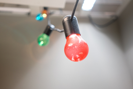 colorful Incandescent light bulb hanging on black  electric wire against grey background for decorationの写真素材