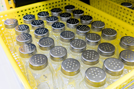 Pepper and salt shaker glass bottles with silver metallic cap in yellow basket.の写真素材