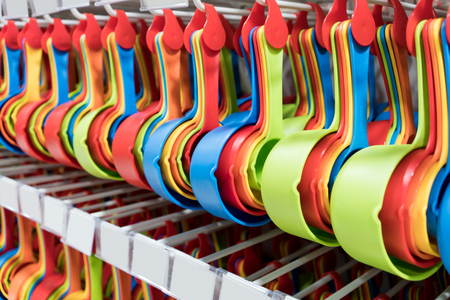 Set of colorful plastic measuring spoons hanging on rack in rows.の写真素材