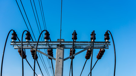High voltage electricity cable connected with brown ceramic insulators installed on concrete pole