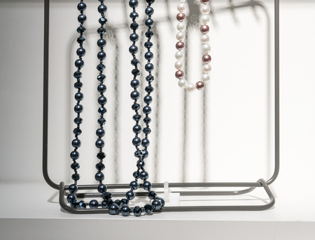 Modern necklaces hanged on a metallic frame on white background