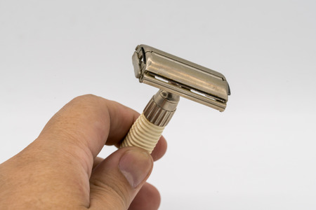Hand holding vintage retro edged razor and shaver isolated on white backgroundの写真素材