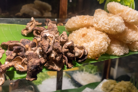 Closed up dried shitake and tremella mushroom, ingredients for noodle in wooden cabinet. A look through mirror of old style food presentation.の写真素材
