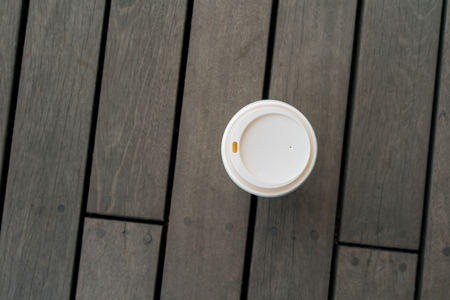 Top view of single hot latte on vintage wooden floor at relaxing balcony. Paper coffee cup with plastic lid.の写真素材
