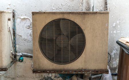Old vintage rusting metal exterior fitted airconditioning unit mounted on wall needing maintenanceの写真素材
