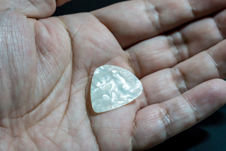 Hand holding whtie plastic guitar plectrum. Guitar Pickの写真素材