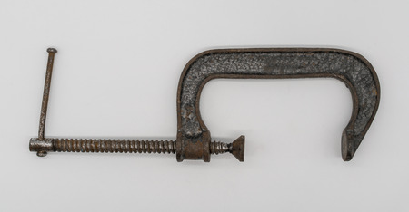 Vintage adjustable  clamp for carpenter work in an old traditional style wood working workshop. Used c-clamp or g-clamp for holding wood or metal isolated on white.の写真素材