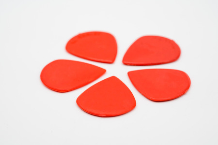 Red plastic guitar picks isolated on white background with shallow depth of fieldの写真素材