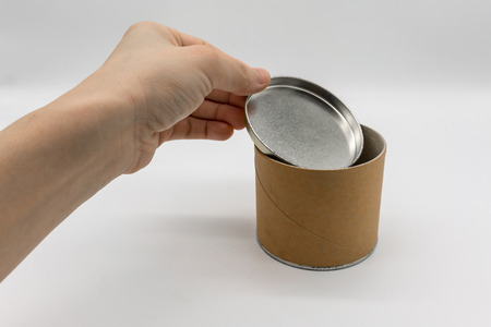 Hand opening cylinder container with metal or tin lid isolated on white background