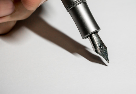 Hand writing the dark silver or gray fountain pen with silver nib isolated on white backgroundの写真素材