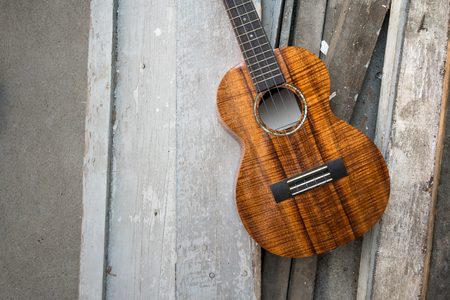 Curly koa ukulele gloss finished against wooden background. Selective focusの写真素材