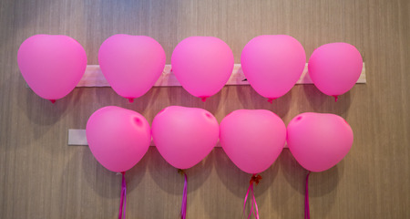 Rows of heart shape pink balloons in parallel lines on wooden wall for valentine decoration.の写真素材