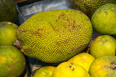 Jackfruit with green spiky skin and big stem in wooden box for sale at fresh market.