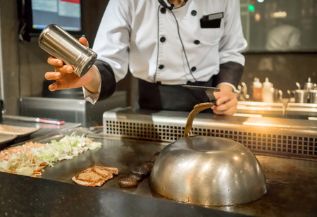 Hand of Chef adding salt into the steak on hot pan in front of customers. Japanese Tepanyaki Steakの写真素材