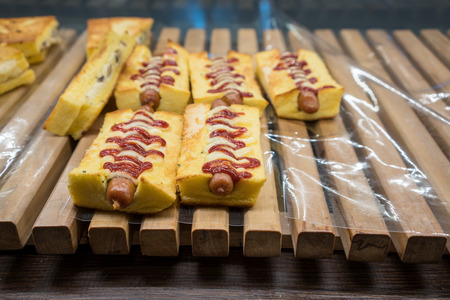 Baked pork sausage with mayonnaise bread on wooden rack in modern bakery shop.の写真素材