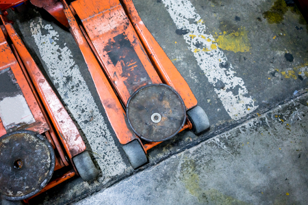 Used and dirty orange hydraulic floor jacks on concrete floorの写真素材