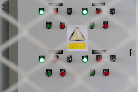 Electric city control panel in grey metal box hanging on wall inside chain link fence cage....