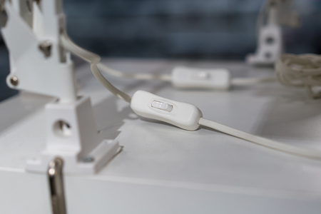 Electrical light On - Off switch for lamp in white plastic case on white table