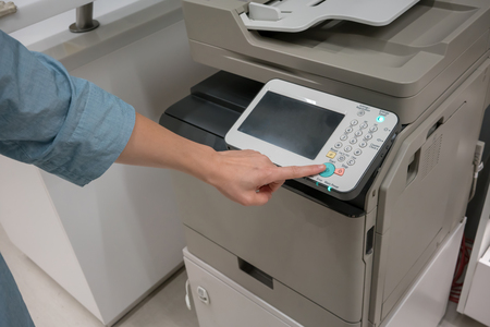 Woman's hands pressing button on copy machine in office or storeの写真素材