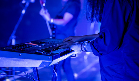 Pianist playing electric piano in concert at night under blue lighting atmosphere, music concept.の写真素材