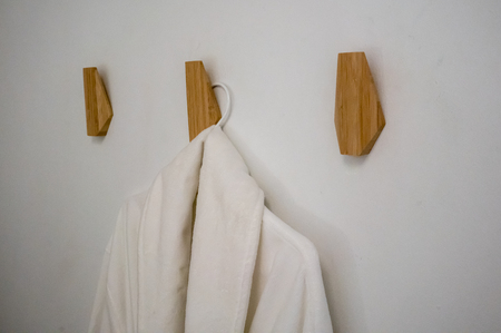 Classic bathrobe hanging on wooden abstract wall hook mounted against white wallの写真素材