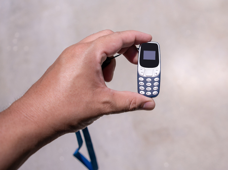 Man hand holding the world smallest mobile phone with OLED screen in blue plastic body. Selective...