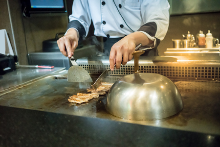 Japanese Chef cooking chiken steak on hot pan in front of customers. Tepanyaki steakの写真素材