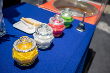 Many colored granulated sugar in glass jar in row on blue table for making cotton candy in luxury restaurant.の写真素材