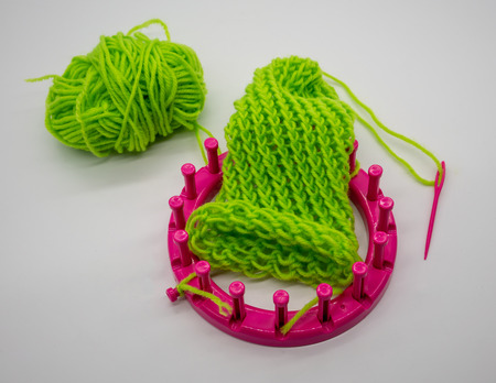 Round knitting loom kit and green yarn with basic stitches isolated on white background.の写真素材