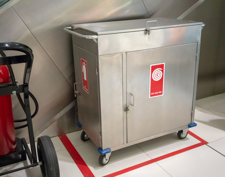 Fire extinguisher and Fire hose reel in  4- wheel stainless steel cabinet in place.の写真素材