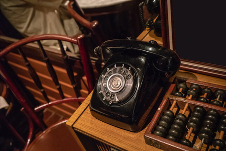 Black vintage phone on wooden table near vintage abacus.の写真素材