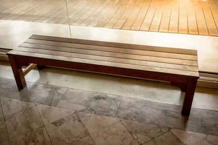 Wooden chair or wood bench inside a building along a walkway. Rest area along pedestrian way.の写真素材