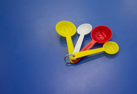 Set of colorful plastic measuring spoon isolated on blue table  background.の写真素材