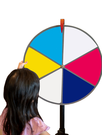 Asian girl trying to spin the huge colorful fortune wheel isolated on white backgroundの写真素材