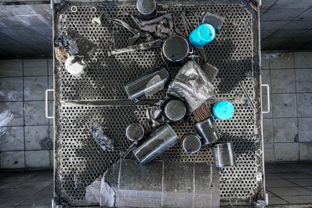 Group of old vehicle parts waste background. Pile of used oil filters from car engine on dirty black metal grillの写真素材