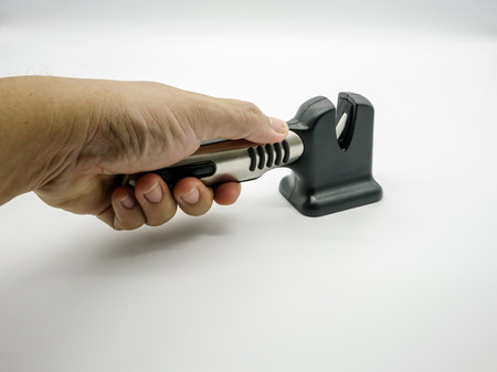 Hand holding black and silver knife sharpener isolated on white backgroundの写真素材