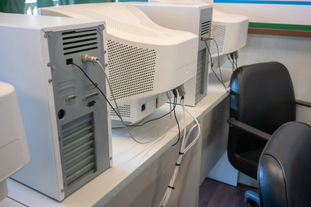 Old CRT computer monitors and towers in classroom.の写真素材