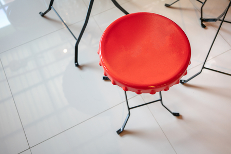 Red metal chair with black metal structure legs on glossy granite tiles floorの写真素材