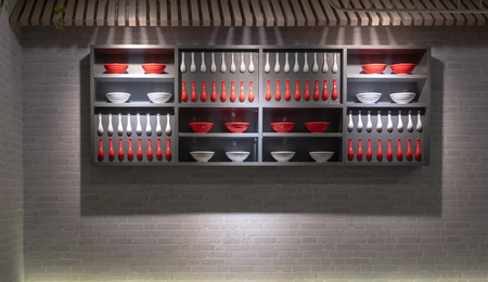Shelf of red and white porcelain bowls and spoons on grey brick wall for interior decoration.の写真素材