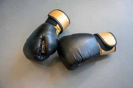 Old black and yellow boxing gloves on grey concrete background. - Imageの写真素材