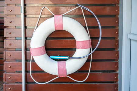 White and red Lifebuoy Ring hanging on wooden wall panel.の写真素材
