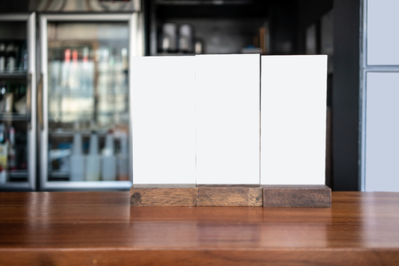 Three white plastic menu board on wooden counter table in front of kitchen.の写真素材