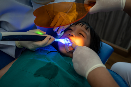 Asian girl getting dental filling treatment at molar tooth with ultraviolet technology.の写真素材