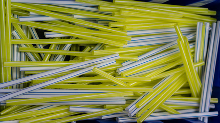 White straws with blue lines and yellow straws with white lines in blue plastick container or...